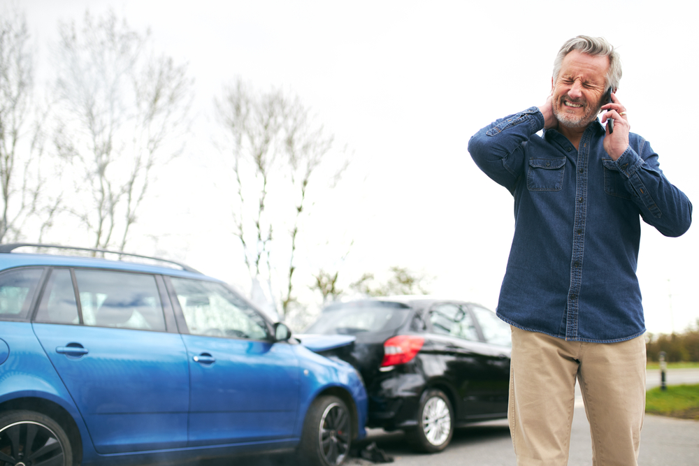 man in whiplash pain after a car accident on the phone